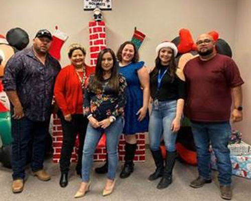CyraCom Las Cruces Center employees pose by holiday decorations