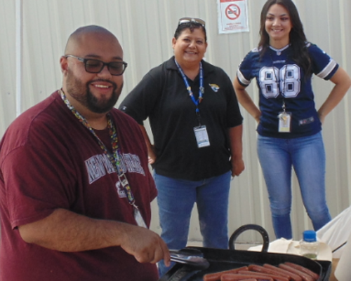 CyraCom Las Cruces Center employees in football shirts grilling