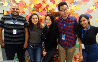CyraCom employees pose in front of autumn decorations