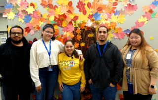 CyraCom Queens Center employees pose by autumn decorations